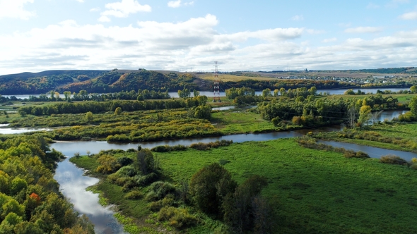 Distant Tower Against River Flowing Among Green Plants alt