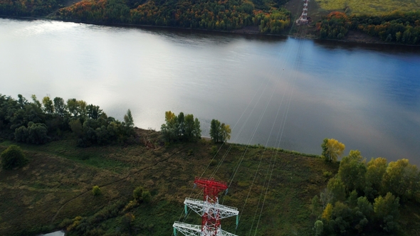 Electrical Transmission Tower on River Bank Among Plants alt