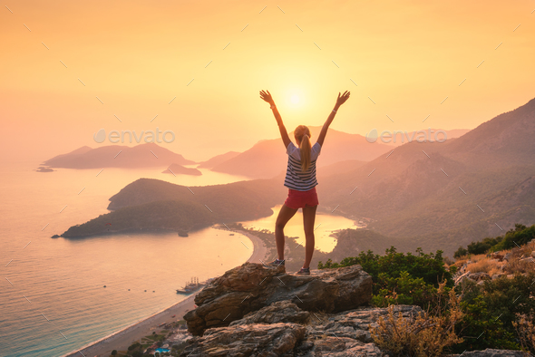 Landscape with woman, sea, mountain ridges and orange sky - Stock Photo - Images