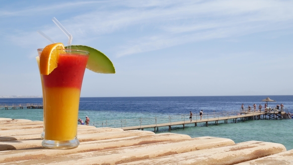 Red Strawberry and Mango Juice on Blue and Turquoise Sea Background or Ocean alt