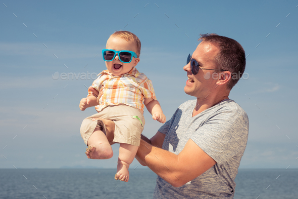 Father and baby son playing on the beach at the day time. - Stock Photo - Images