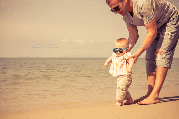 Father and baby son playing on the beach at the day time. - Stock Photo - Images