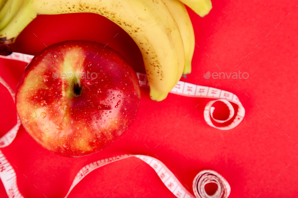 Measuring tape wrapped around a red apple and banana - Stock Photo - Images
