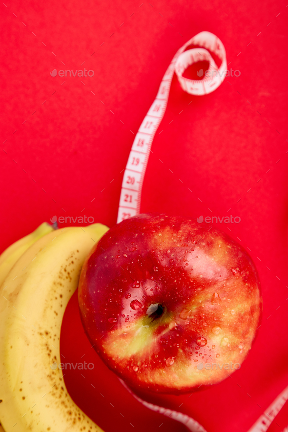 Measuring tape wrapped around a red apple and banana - Stock Photo - Images