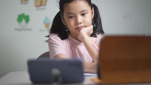 Asian child student study online on computer tablet or kid girl learn from home school by video call alt