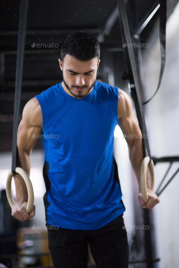 man working out pull ups with gymnastic rings Stock Photo by dotshock