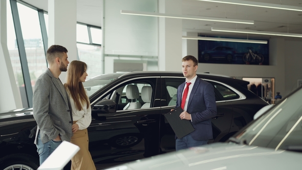 Car Dealership Worker Is Talking To Beautiful Couple Bearded Man and His Attractive Wife While alt
