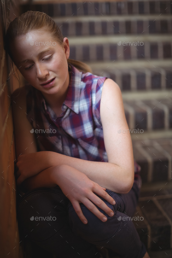 Sad schoolgirl sitting alone on staircase Stock Photo by Wavebreakmedia