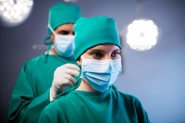 Surgeon helping a nurse in tying surgical mask in operation room Stock ...