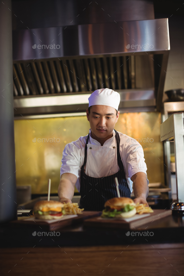 Chef placing tray with french fries and burger at order station