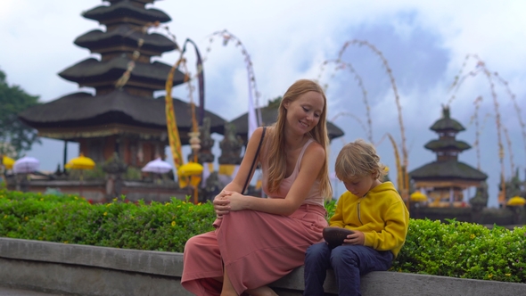 Young Woman and Her Son Sitting in Front of a Pura Ulun Danu Temple on the Lake Bratan in Bali alt