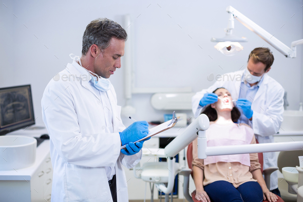 Dentist writing on clipboard - Stock Photo - Images