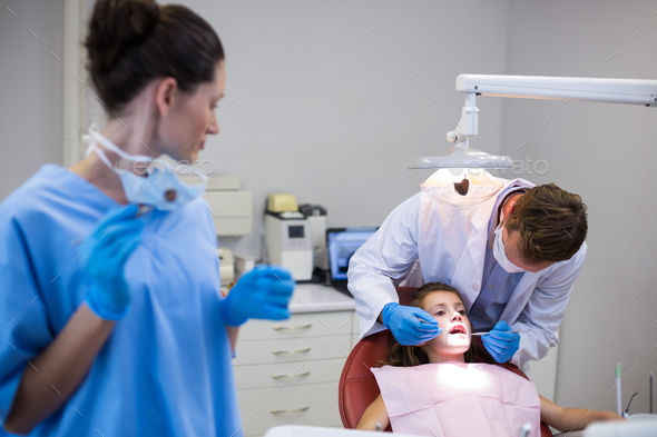 Dentist examining a young patient with tools - Stock Photo - Images