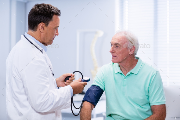 Doctor Checking Blood Pressure Of A Patient Stock Photo By Wavebreakmedia