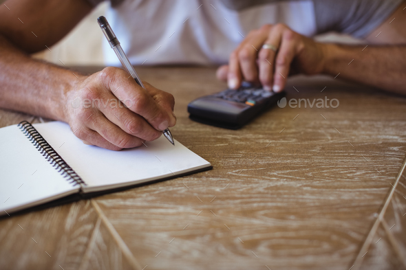 Man using calculator to calculate expenses - Stock Photo - Images