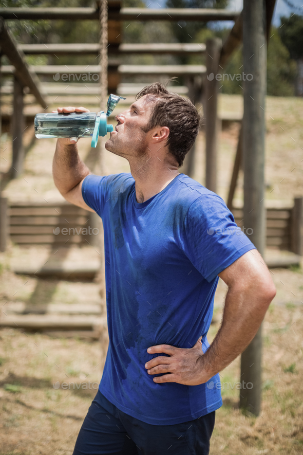 Man drinking water from bottle during obstacle course - Stock Photo - Images