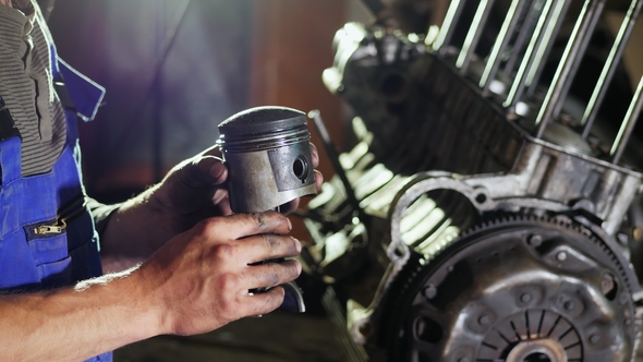 The Mechanic Holds in His Hands the Spent Piston of the Car alt