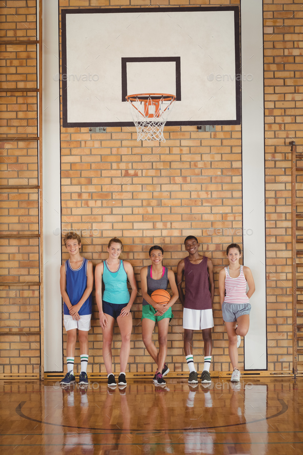 High school kids leaning against the wall in basketball court Stock
