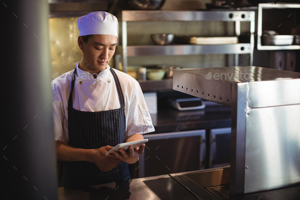 Chef using digital tablet in the commercial kitchen Stock Photo by Wavebreakmedia