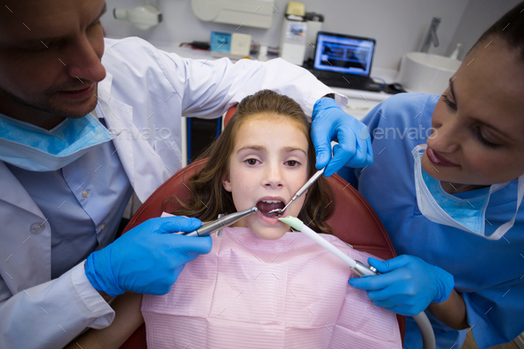 Dentists examining a young patient with tools Stock Photo by Wavebreakmedia