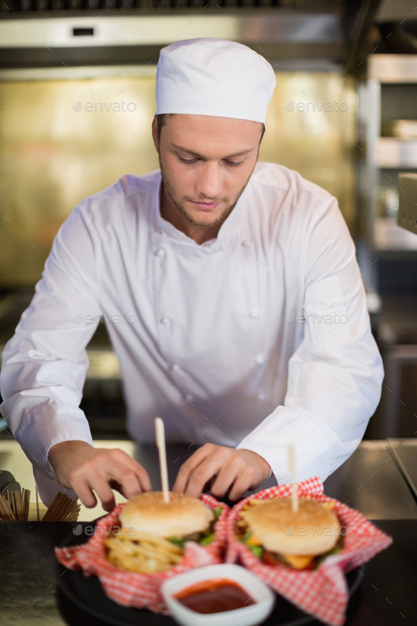 Serious male chef preparing burger in commercial kitchen Stock Photo by