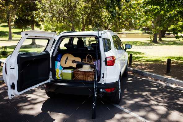 Guitar, fishing rod, picnic basket in car trunk Stock Photo by