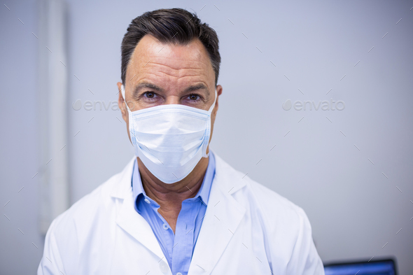 Dentist wearing surgical mask in dental clinic Stock Photo by Wavebreakmedia