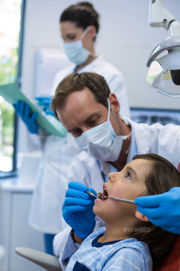 Dentist examining a young patient with tools Stock Photo by Wavebreakmedia