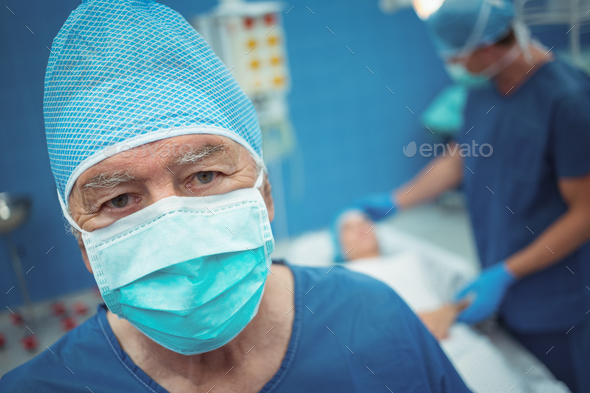 Portrait of male surgeon wearing surgical mask in operation theater - Stock Photo - Images