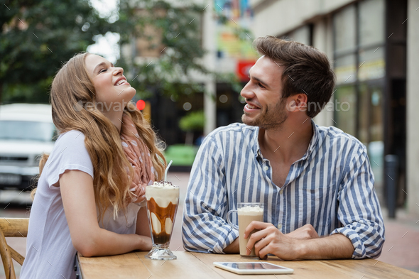 Happy couple laughing while sitting at sidewalk cafe - Stock Photo - Images