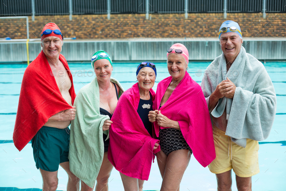 Happy senior swimmers covered in towels at poolside - Stock Photo - Images