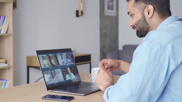 Side View of Indian Man Having Video Call with Diverse People on Pc alt