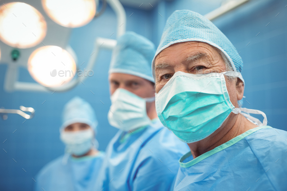 Portrait of male surgeon wearing surgical mask in operation theater Stock Photo by Wavebreakmedia