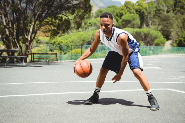 Full length of teenage boy practicing basketball Stock Photo by ...