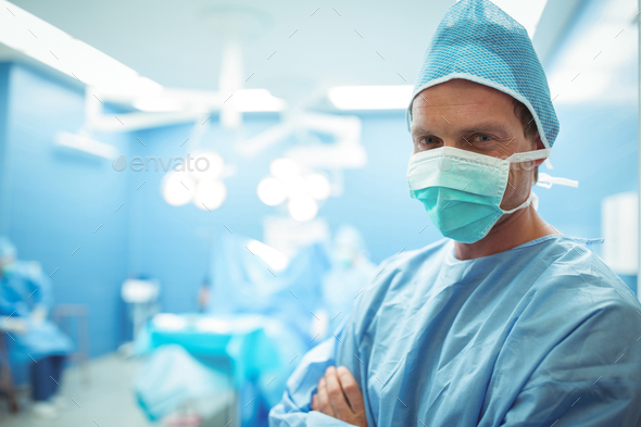 Portrait of male surgeon wearing surgical mask in operation theater Stock Photo by Wavebreakmedia