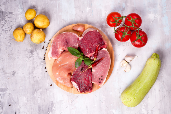 Selection of different raw meat with vegetables at wooden board .Lean proteins. - Stock Photo - Images