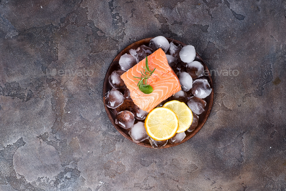 Salmon steaks on ice with lemon slice on wooden plate. Lean proteins. - Stock Photo - Images