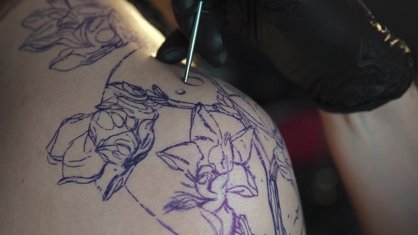 Drawing a Tattoo on the Shoulder . Master Tattoo Makes a Rotary Tattoo Machine Gun