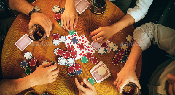 Top view photo of friends sitting at wooden table. Friends having fun while playing board game. Stock Photo by master1305