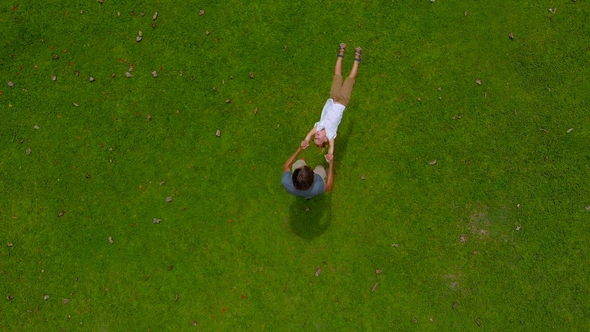 Aerial  Shot of a Father Circling His Son in His Arms on a Green Lawn. Camera Raises Up alt