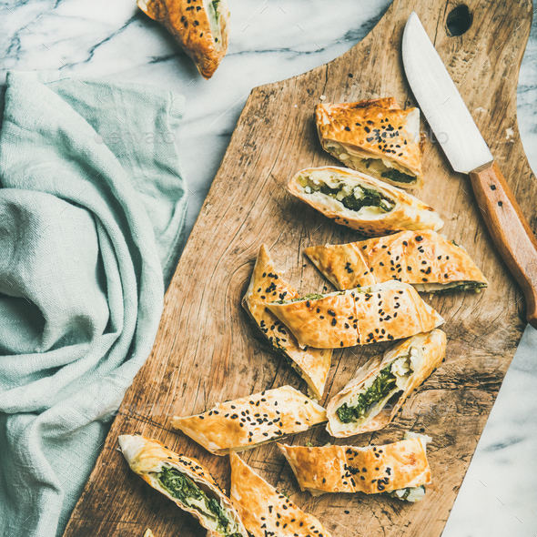Freshly baked Turkish borek roll cut in slices, square crop - Stock Photo - Images