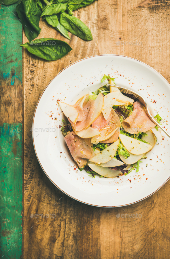 Fresh salad with smoked turkey ham and pear, rustic background - Stock Photo - Images