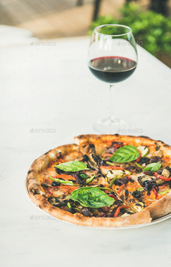 Freshly baked vegetarian pizza and glass of wine Stock Photo by sonyakamoz