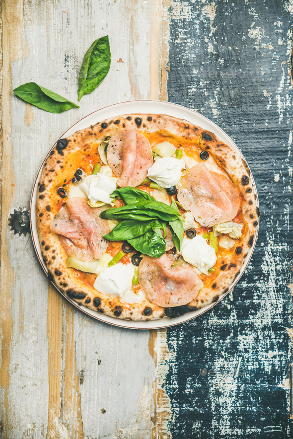 Freshly baked pizza with ham, artichokes, cheese, basil, top view - Stock Photo - Images