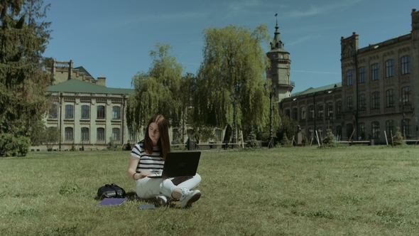 Pretty Female Student Working on Laptop on Lawn alt