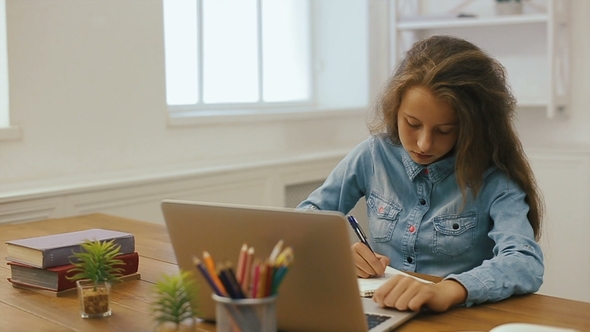 Young Girl with Laptop Computer Is Doing Homework College Education
