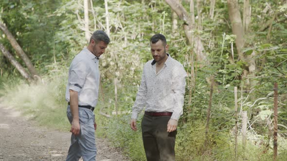 Gay couple during a photo shoot before their wedding in a forest alt