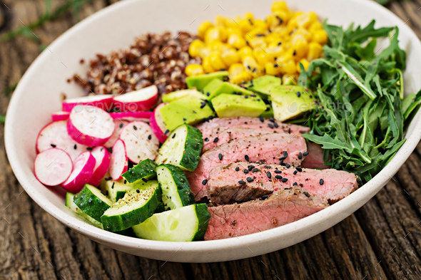 Buddha bowl lunch with grilled beef steak and quinoa, corn, avocado, cucumber Stock Photo by Timolina