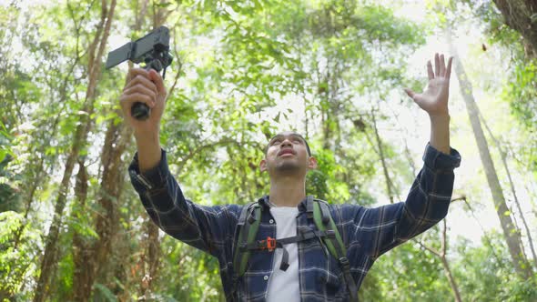 Asian handsome male backpacker vlogger traveling in the forest alone. alt