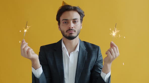 Slow Motion Portrait of Upset Mixed Race Person Waving Sparklers and Looking at Camera with Boredom alt